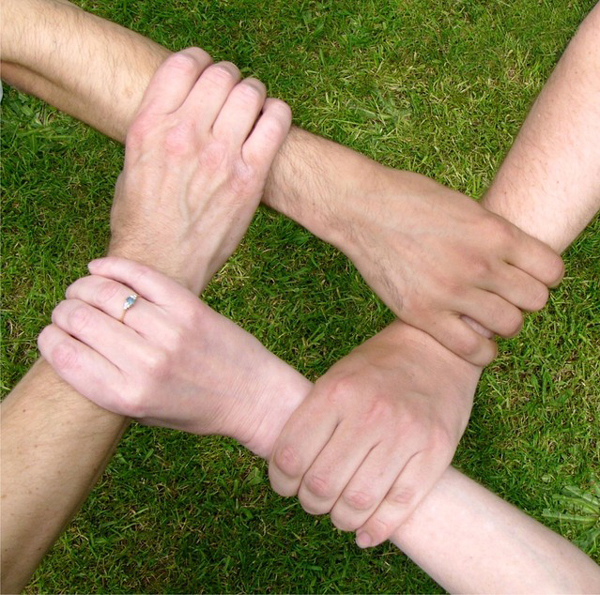 Hands together for team building activities over grass.