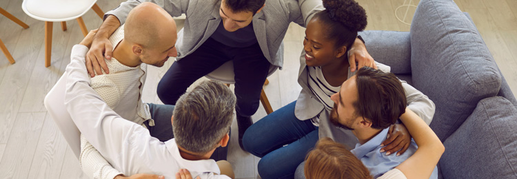 Team of people hugging in office