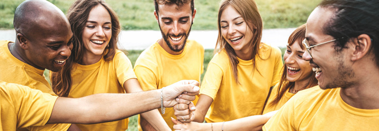 Multiracial happy young people stacking hands outside