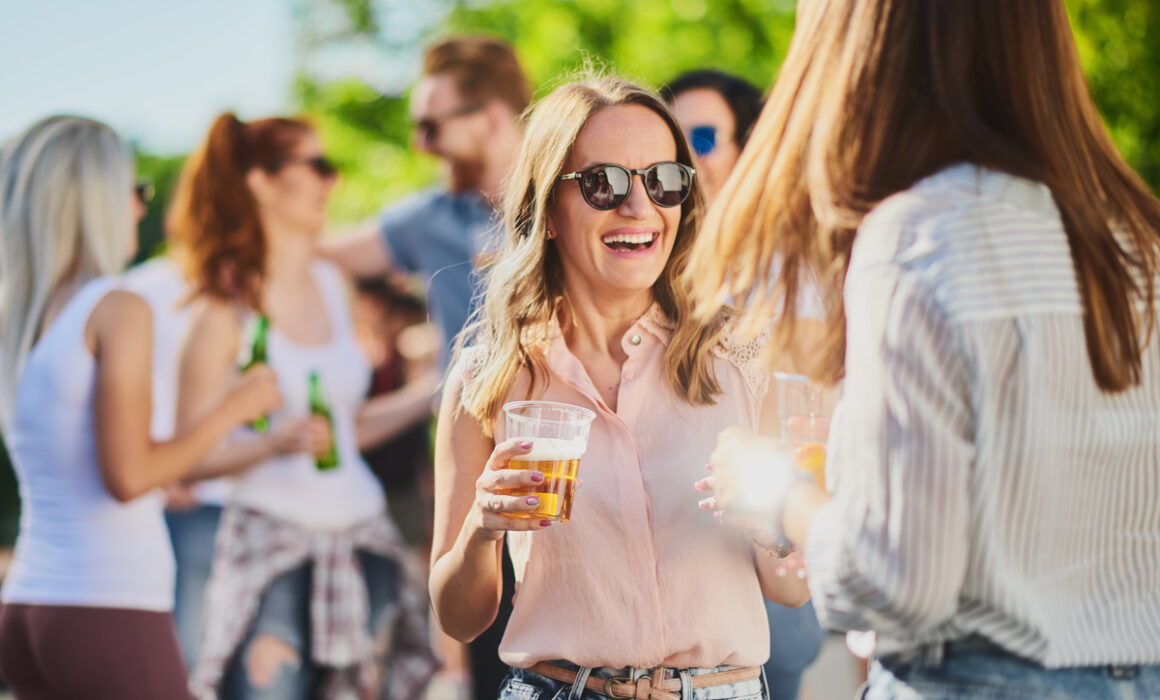 Group of people standing, drinking an having a good time at outdoor party