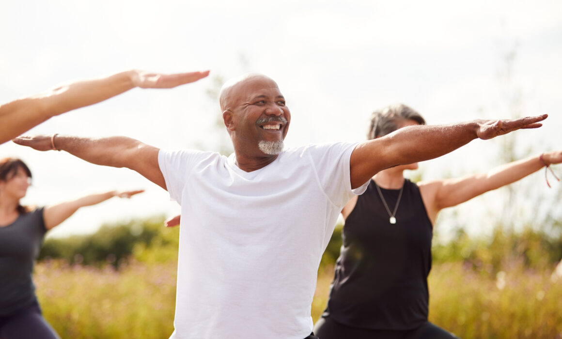Group Of Mature Men And Women In Class At Outdoor Yoga Retreat