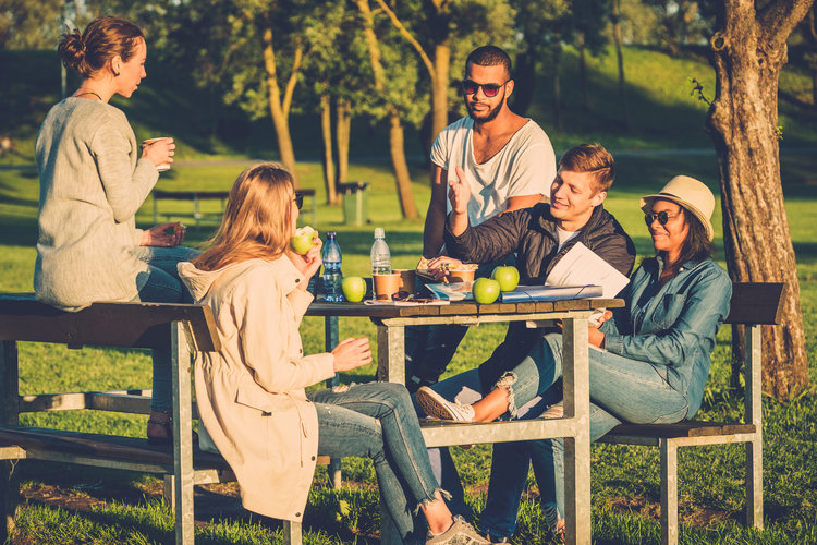 Multi ethnic group of friends drinking coffee and chatting in a park